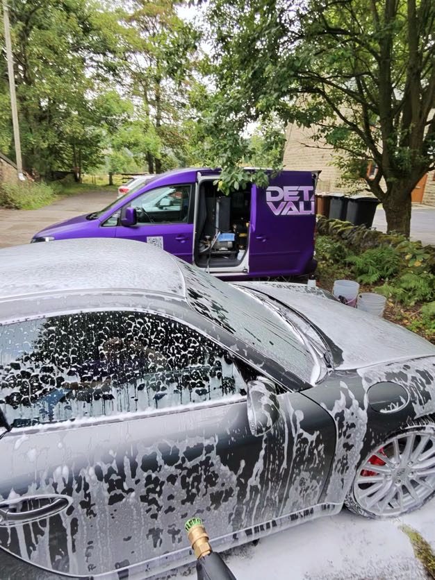 Car covered in snow foam on a driveway next to the Detail Valets van