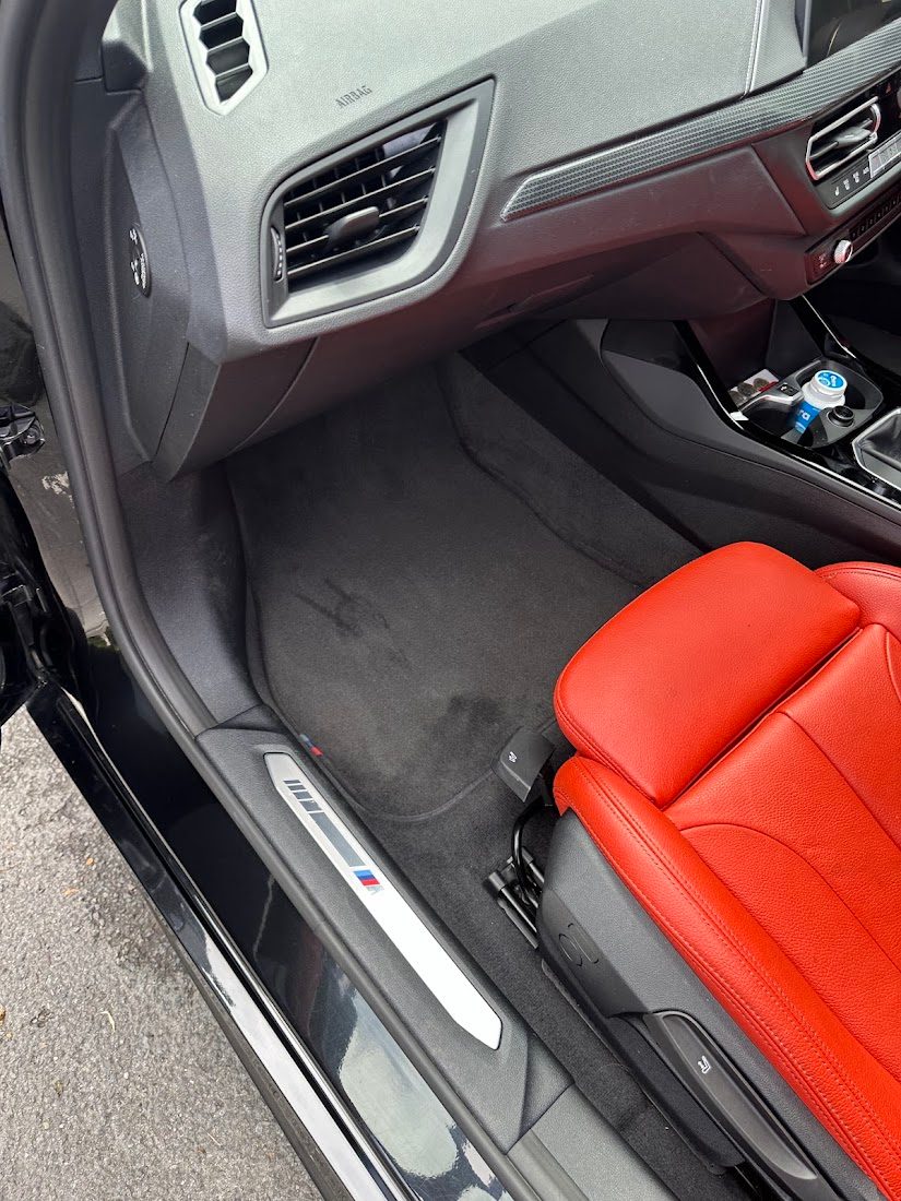 The same footwell and red leather seat after mobile interior car valeting in Manchester