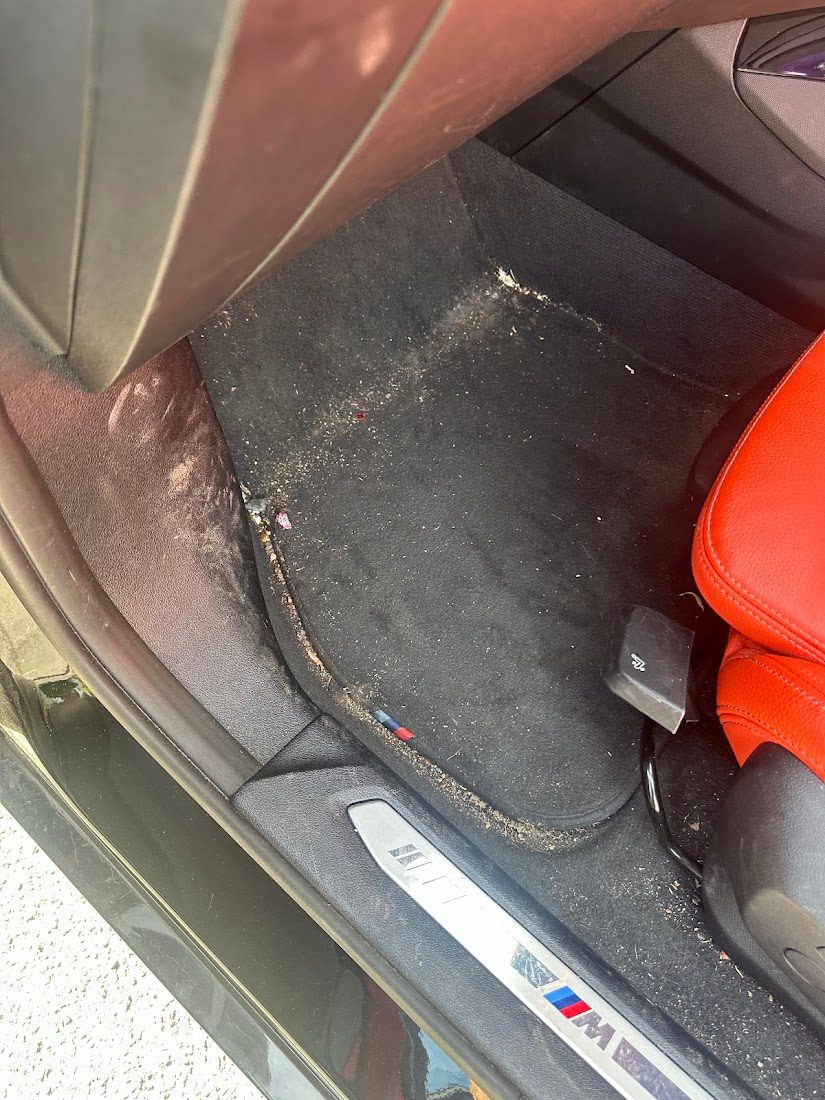 Car footwell carpet covered in grit and crumbs before an interior valet