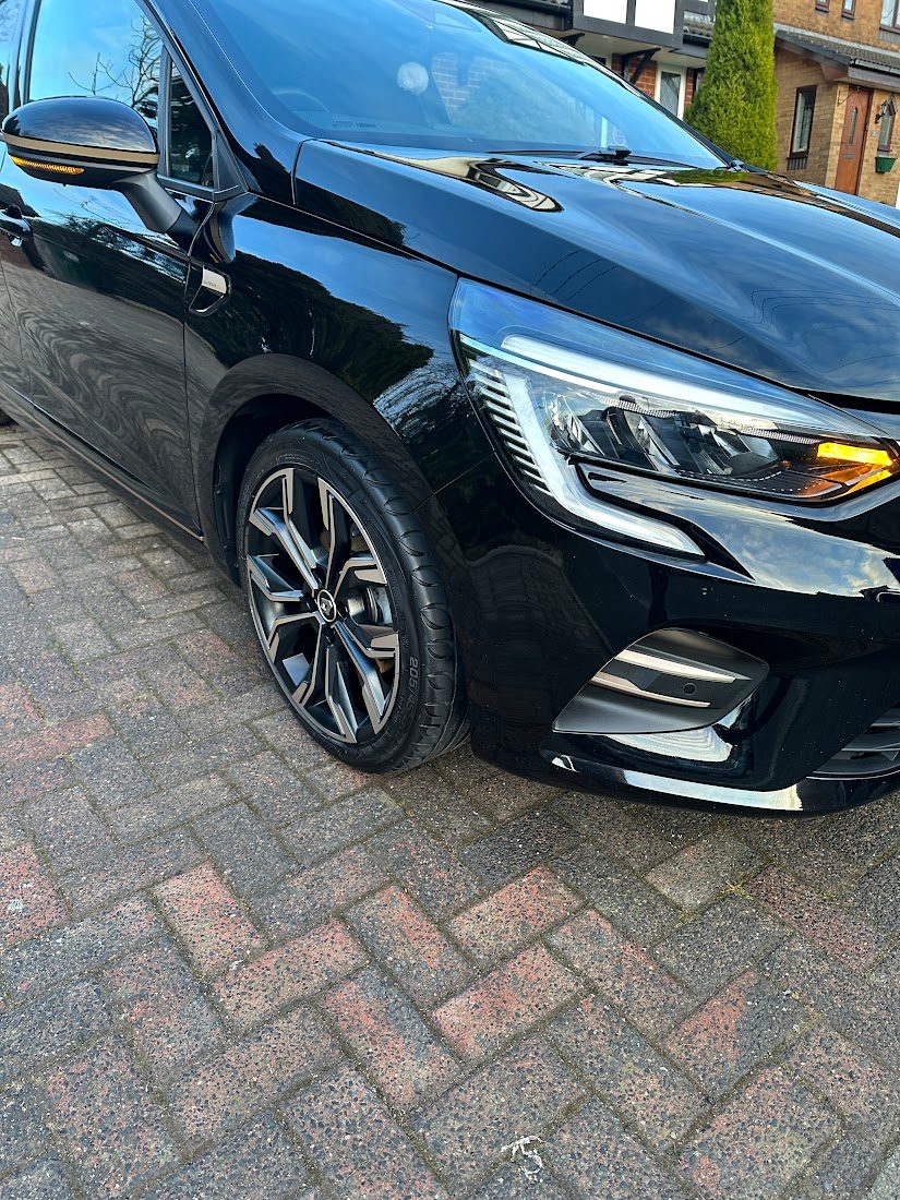 Front of a black Renault Clio with glossy paint and clean wheels on a driveway